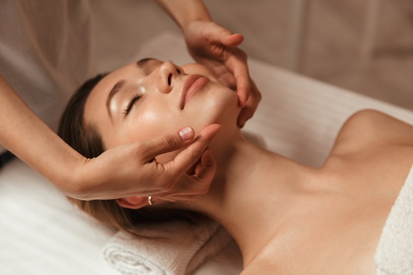 Young woman getting spa treatment with head massage at a spa center.