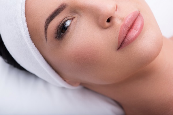 Beautiful woman laying on a pillow following a permanent makeup appointment.